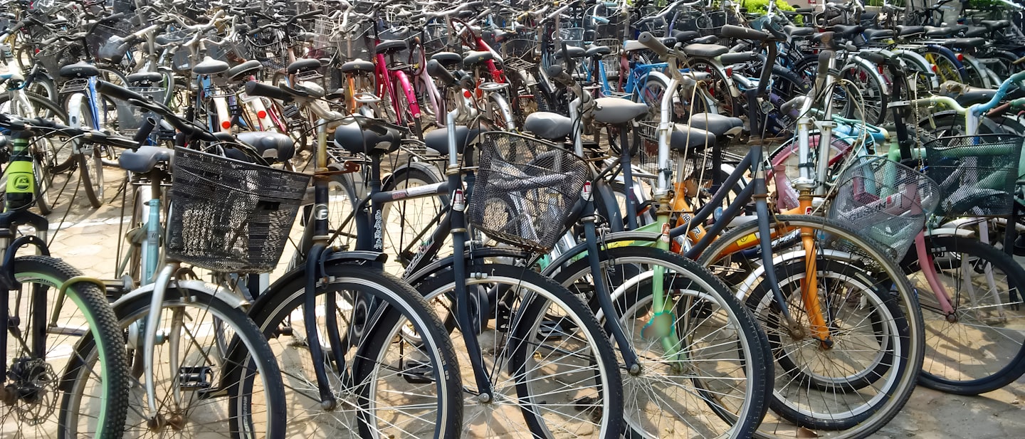 Molte biciclette con cestini parcheggiate insieme in un piazzale all'aperto.