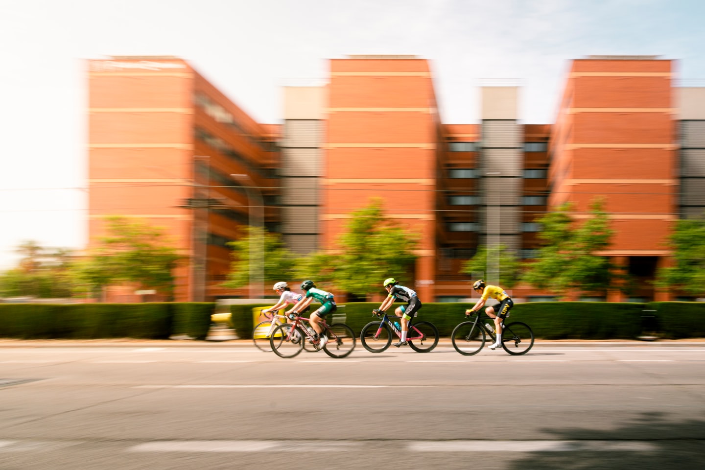 Quattro ciclisti in bicicletta insieme su una strada asfaltata.