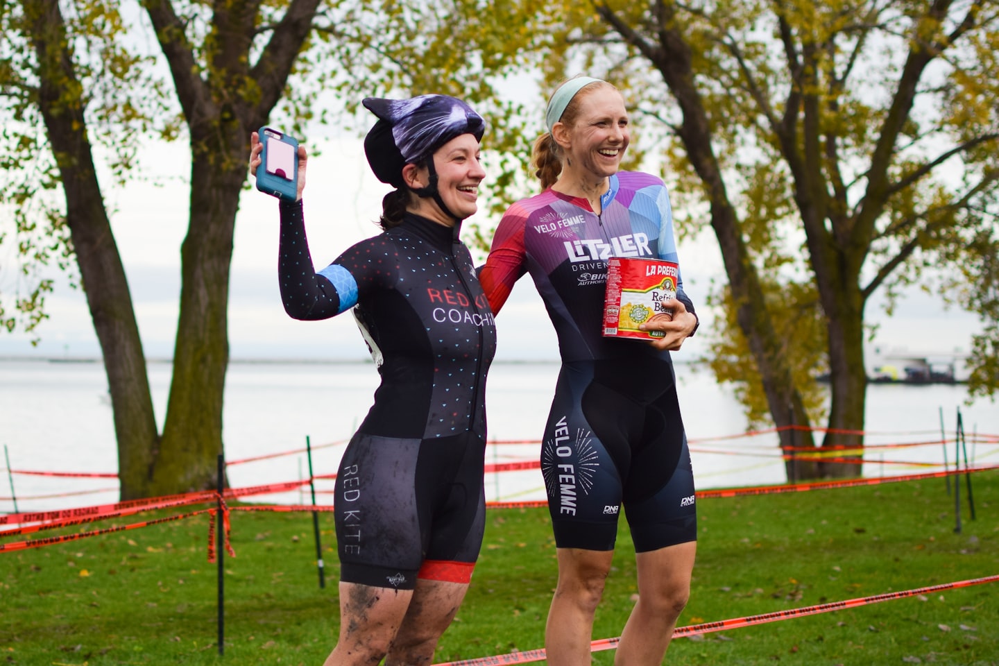 Due donne felici festeggiano una gara ciclistica di successo con cibo e un telefono.